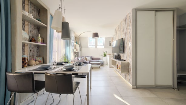 A modern kitchen with a dining area, a sofa, and a TV.
