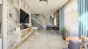 A modern living space with a kitchen, dining area, and staircase.