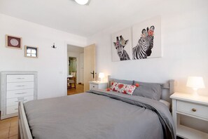 A bedroom with a bed, nightstands, a dresser, and wall art.