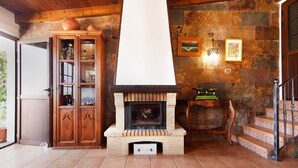 A stone fireplace with a chimney, a wooden cabinet with glass doors, and a staircase with patterned tiles. - Holiday Home 'Villa Floti With Sea View' with Sea Views, Wi-Fi and Air Conditioning (Telde)