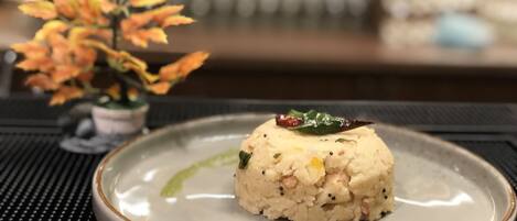 Un plato con una porción de arroz y una hoja verde encima, sobre un mantel con textura.