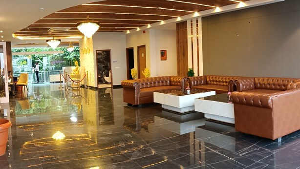 A modern lobby with a polished marble floor, leather seating, and a wooden ceiling design. - SPT Clarks Inn Suite Mandi  (Balichauki)