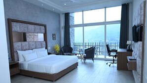 A modern hotel room with a large bed, a desk, a chair, and a TV. - SPT Clarks Inn Suite Mandi  (Balichauki)