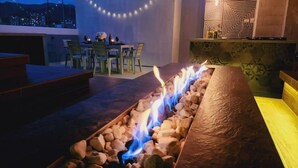 A fire feature with rocks and a stone bench, a dining area with chairs and a table, and a patterned wall. - Luxury 4 /jacuzzi/terrace/private/cerca Al Poblado (Medellín)