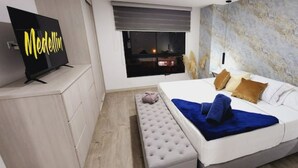 A modern bedroom with a large bed, a TV on a stand, and a view of the city at night. - Luxury 4 /jacuzzi/terrace/private/cerca Al Poblado (Medellín)
