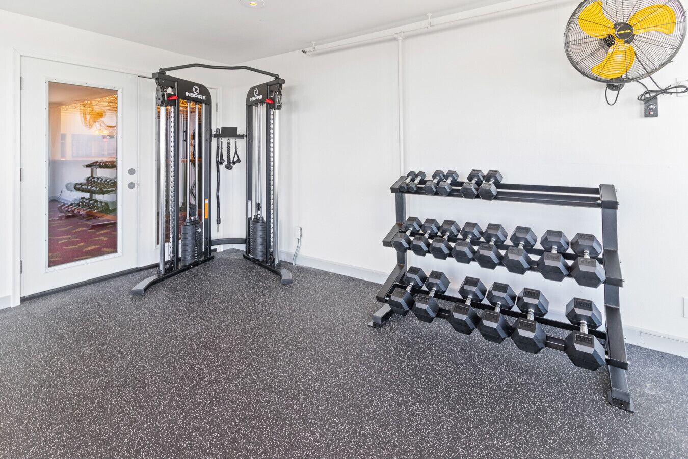A home gym with a pull-up bar, weight stack, and a rack of dumbbells.