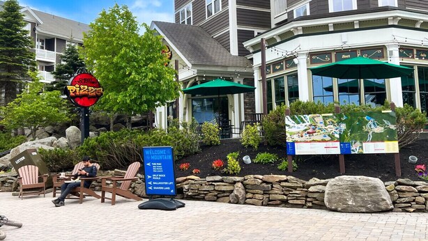 Un hôtel avec une enseigne indiquant « Bienvenue à la montagne » et un restaurant appelé « Les Abeilles ».