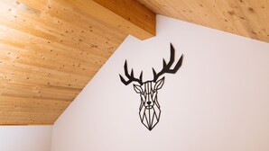 A geometric deer head wall decal in a room with wooden ceiling beams and a wooden railing.