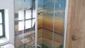 Une douche entièrementClose avec une fresque représentant un paysage montagneux.