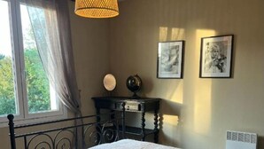 A bedroom with a bed, a desk, a chair, a lamp, and a radiator. - Chez Caroline Ingalls (Gavray-sur-Sienne)