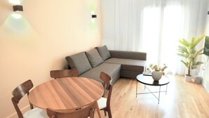 Een moderne woonkamer met een houten eettafel, een grijze bank en een klein bijzettafeltje met een vaas.