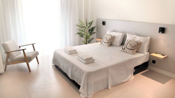 Een moderne hotelkamer met een groot bed, een stoel, een nachtkastje en een potplant.