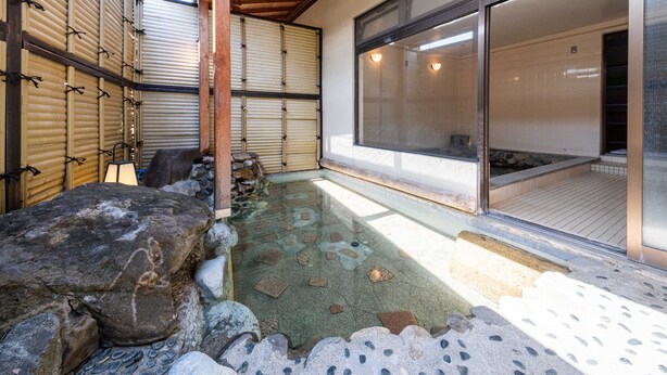 A traditional Japanese-style room with tatami flooring, a stone water feature, and sliding doors.