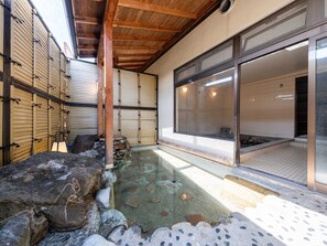 Et traditionelt japansk værelse med tatamimåtter, en stenfountain og skydedøre.
