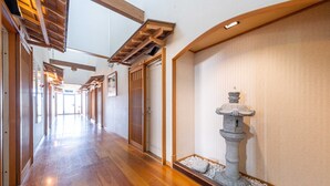 A hallway with wooden flooring, a stone water feature, and wooden doors.