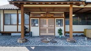A traditional Japanese building with a wooden entrance, a tiled roof, and a gravel ground.