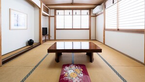 A traditional Japanese room with tatami flooring, a low wooden table, sliding shoji doors, and a framed picture on the wall.