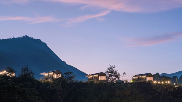 Une rangée de chalets modernes, avec une vue sur les montagnes, chacun doté d’un balcon et éclairé par un système d’éclairage d’ambiance.