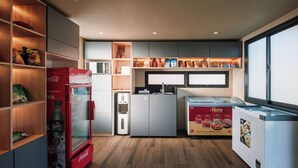 Une cuisine compacte équipée d’un réfrigérateur, d’un four à micro-ondes et d’un distributeur de boissons.