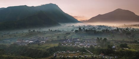 A rural landscape with a village, houses, and mountains.