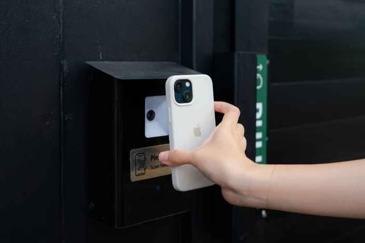 Een hand houdt een smartphone vast bij een deur met een QR-code om te scannen.