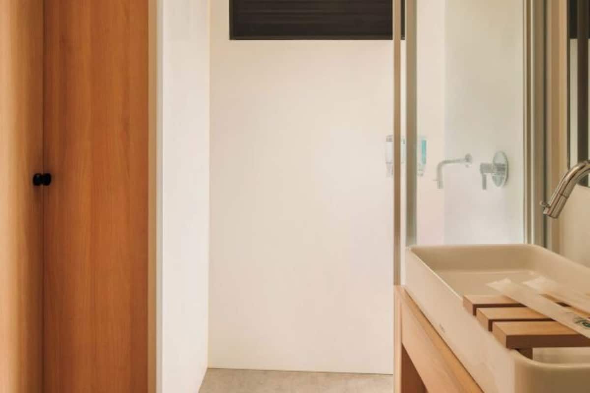 Een moderne badkamer met een houten wastafelmeubel, een douchecabine van glas en een witte deur.