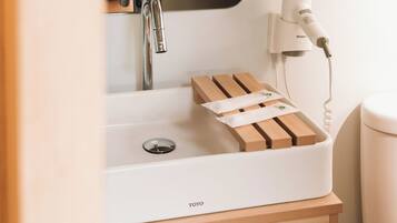 A bathroom with a white sink, a mirror, a hairdryer, and a wooden soap dish.