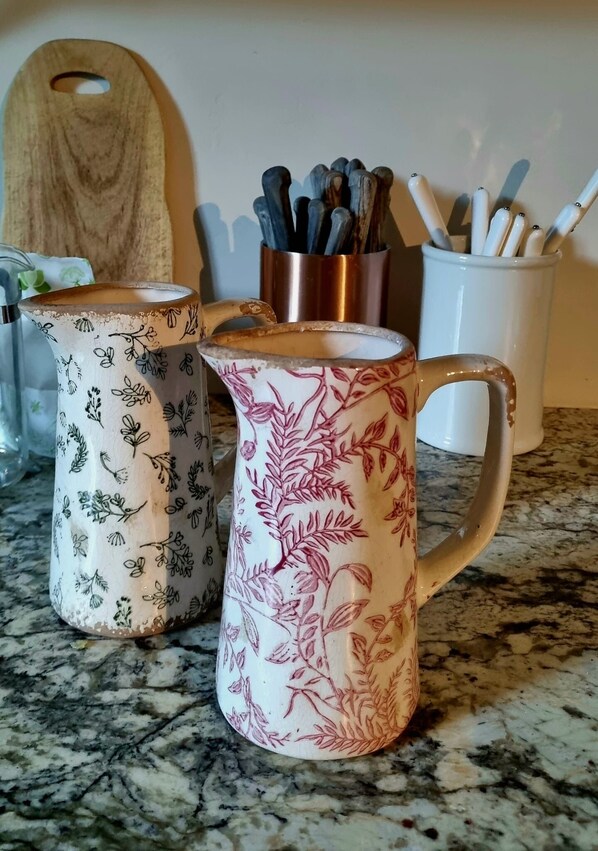 Trois tasses en céramique ornées de motifs floraux, posées sur un comptoir de cuisine.