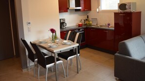 A compact kitchen with a dining table, chairs, and a microwave. - Charming Gîte with Garden and Child's Play Area - Near Altkirch Center (Altkirch)