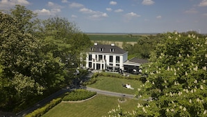 A large, two-story house with a symmetrical facade, surrounded by lush greenery and a well-maintained lawn. - Luxe overnachten in Zeeland (Rilland)