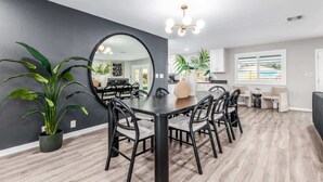 A modern dining area with a round table, black chairs, and a large mirror. - The Monterey | Pool, Sport Court & Putting Green (Scottsdale)
