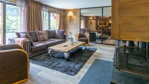 Ein modernes Wohnzimmer mit einer Couch, Sesseln, einem Couchtisch und einem Kamin.