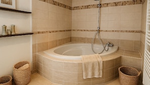 Ein Eckbadezimmer mit einer freistehenden Badewanne, einer Duschbrause und zwei Korbwannen.