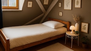Ein Schlafzimmer mit einem hölzernen Bett, einem Nachttisch mit Lampe und gerahmten Pflanzenbildern an der Wand.