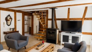 Ein Wohnzimmer mit Holzboden, einer Holztreppe, einem Fernseher und einem Kamin.