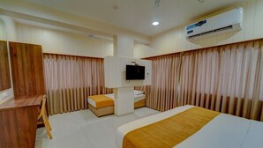 Ein Hotelzimmer mit Bett, Schreibtisch, Stuhl, Fernseher und Klimaanlage.