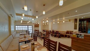 Ein Restaurant mit mehreren Tischen und Sitzgruppen, Holzbänken und Pendelleuchten.