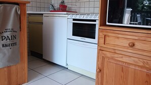 Eine Küche mit einem weißen Ofen, einem Geschirrspüler und einem Holflanschrank mit einem Samsung Fernseher.