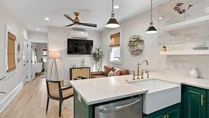 Une cuisine moderne dotée d’un îlot central, de meubles de couleur verte et de luminaires suspendus.