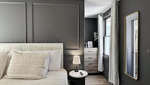 Une chambre à coucher avec un grand lit, une table de chevet avec une lampe, une commode et un miroir au mur.