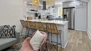 Une cuisine moderne dotée d’un îlot central, de tabourets de bar et de luminaires suspendus.