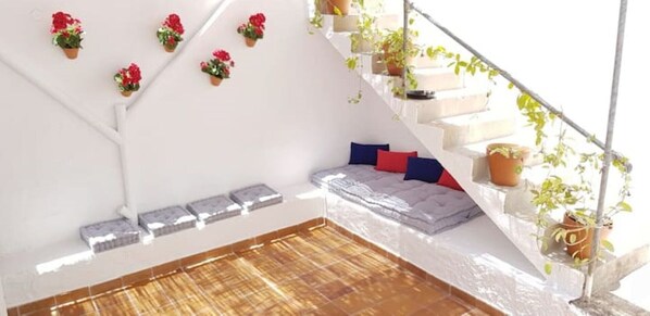 A modern room with a built-in bench, a staircase with plants, and a bed with pillows.