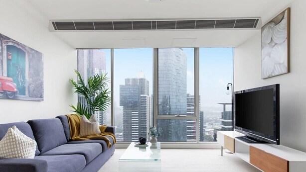 A modern living room with a large window, a sofa, a coffee table, and a TV on a stand. - Comfy & Stylish 2BR Apt Next to Crown, City Views (Southbank)