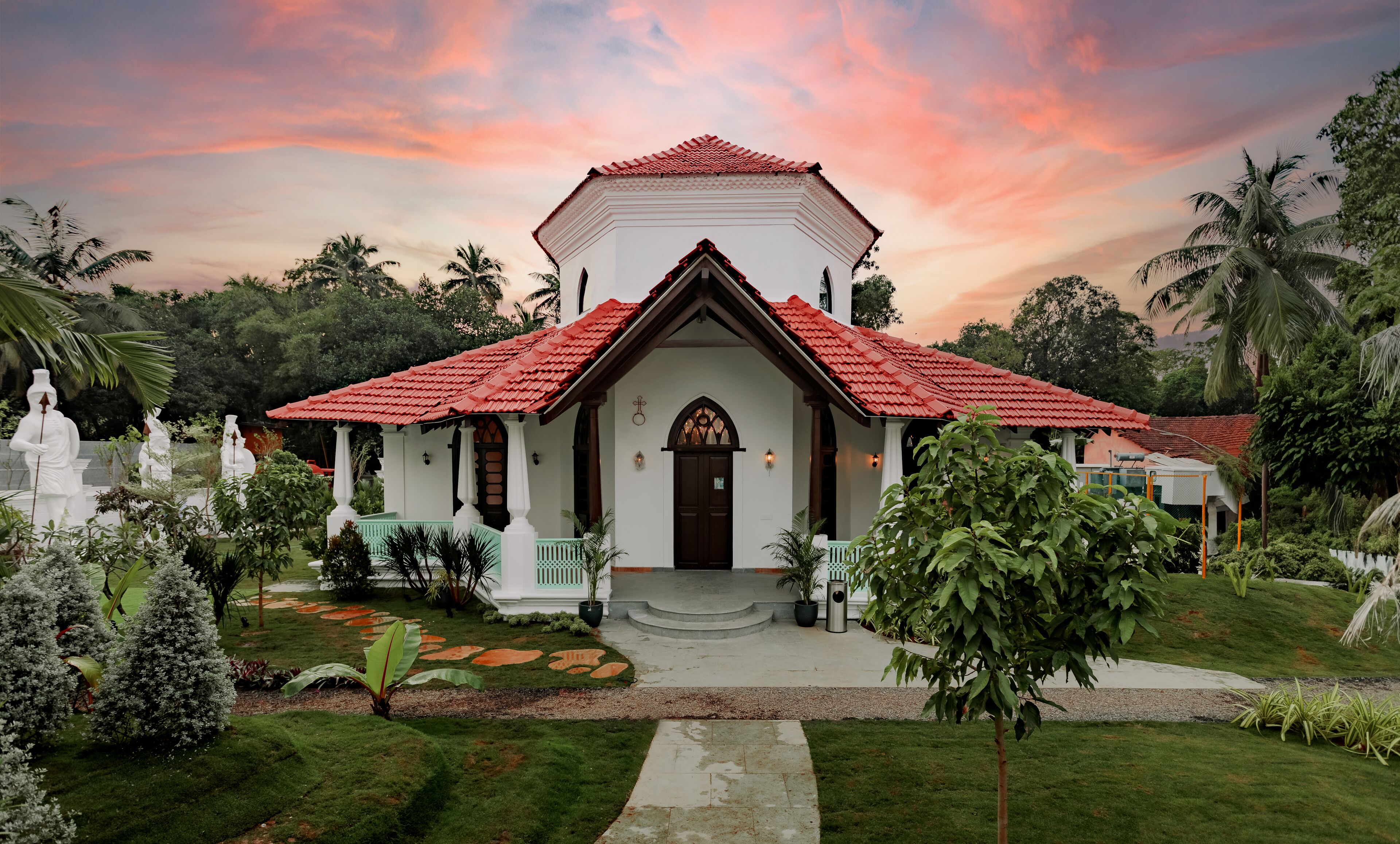 A church with a red-tiled roof, white walls, and a central entrance with steps leading up to it.