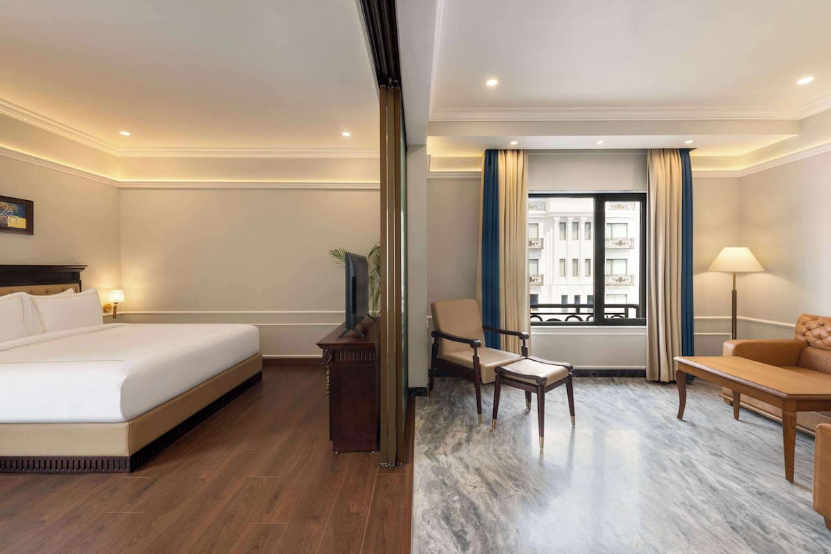 A hotel room with a bed, a desk, a chair, and a sofa.