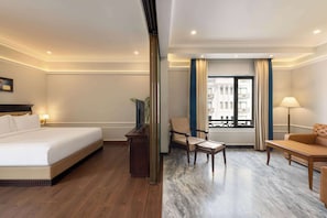 A hotel room with a bed, a desk, a chair, and a sofa. - Ramada by Wyndham Goa Vagator (Vagator)