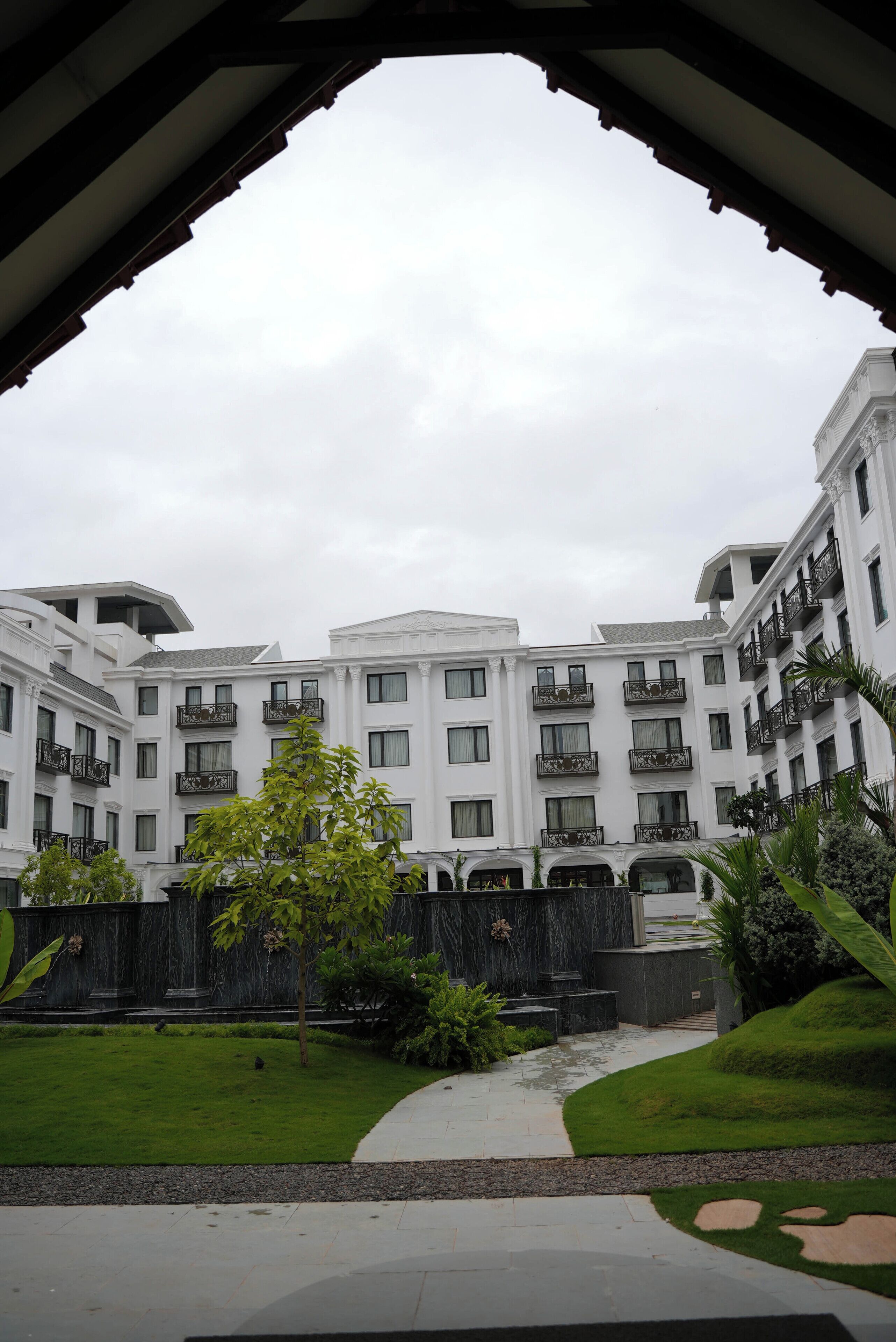 A multi-story building with balconies, a well-maintained lawn, and a pathway leading to the entrance.