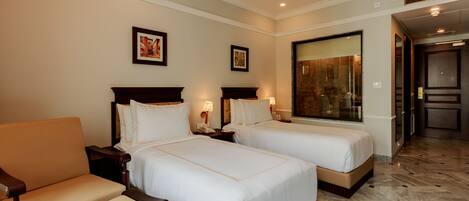 A hotel room with two beds, a sofa, and a large window.