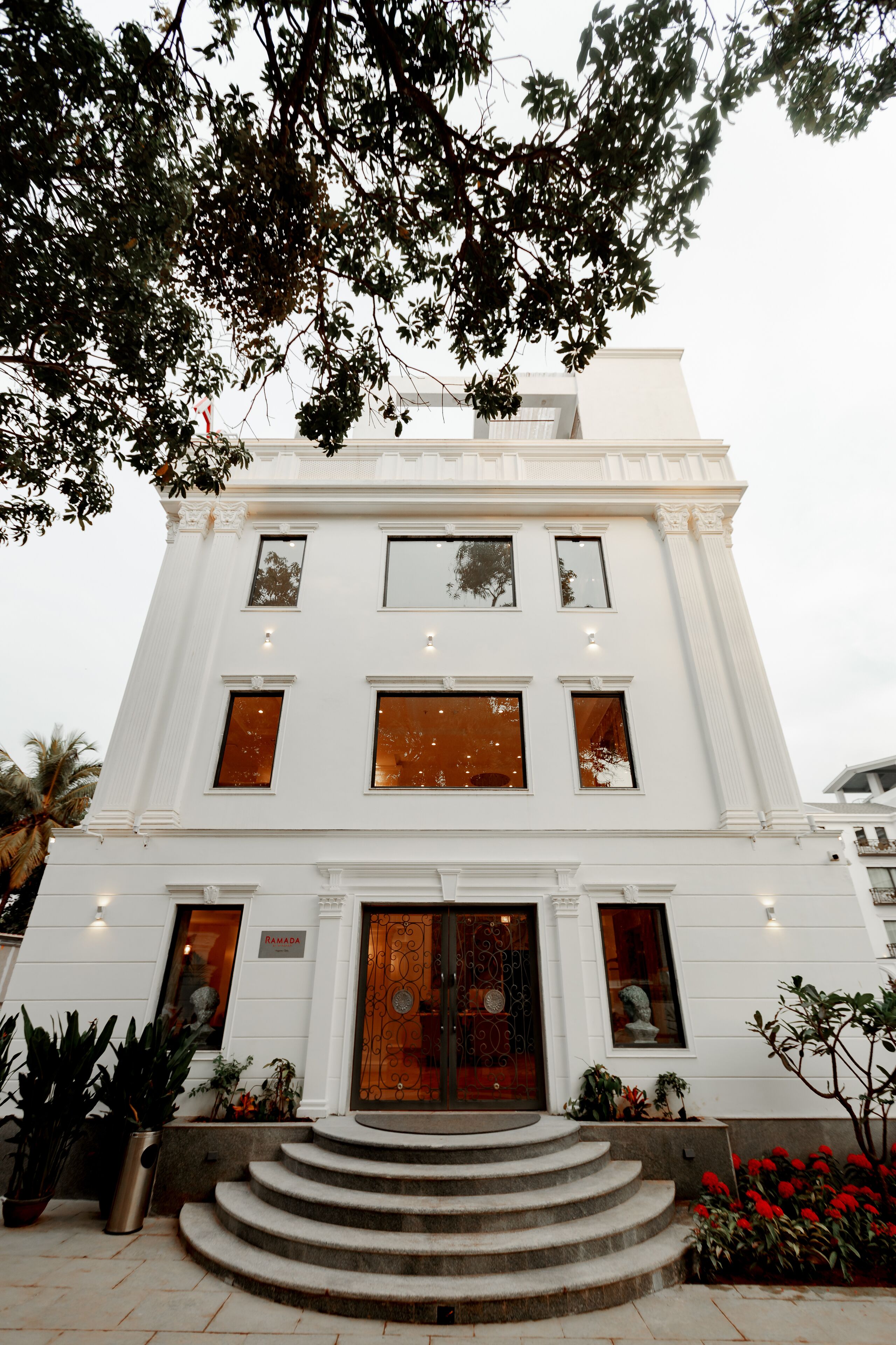 Um edifício branco com uma entrada imponente, várias janelas e uma escadaria que leva à porta.