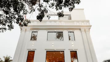 Um edifício branco com uma entrada imponente, várias janelas e uma escadaria que leva à porta.